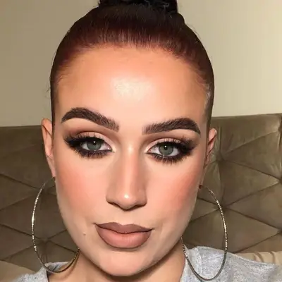 Woman with soft glam eye makeup, long lashes, flushed cheeks, and tan lips