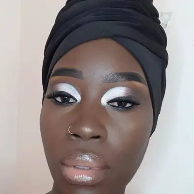 Woman with silver and black eyeshadow, head wrap, and glossy lips