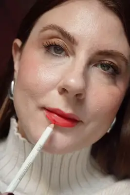 woman with partially applied red lip liner, a pencil to her bottom lip