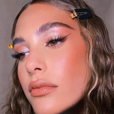 Model with shimmering eyeshadow, winged liner, and neutral blush and lipstick