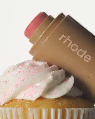 Rhode Pocket Blush in Sprinkle posed against a sprinkle-covered cupcake.