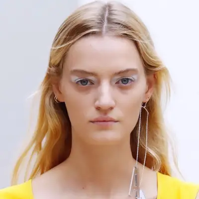 Model wearing graphic white eyeshadow and minimal face makeup