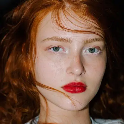 Model with subtle white eyeliner and eyeshadow and red lipstick