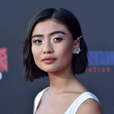 Brianne Tju wears white eyeshadow, flushed cheeks, and a wavy bob hairstyle