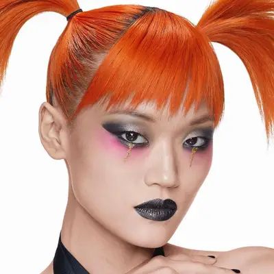 Model wears black lipstick with subtle sheen and multicolored eye makeup with glitter tears