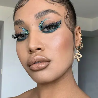 Model wears teal eye makeup with rhinestones