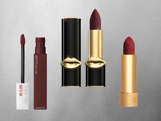 Various dark lipsticks like Pat McGrath Labs MatteTrance Lipstick, Maybelline SuperStay Matte Ink Lip Color, Gucci Velvet Matte Lipstick on a grey background