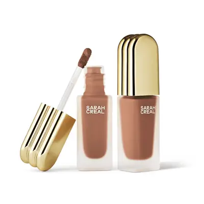 Concealer bottle with a clear base and gold top. Medium deep skin tone produt.
