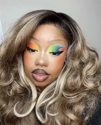 model is wearing a graphic eyeshadow look that has yellow, green. blue, orange, and pink