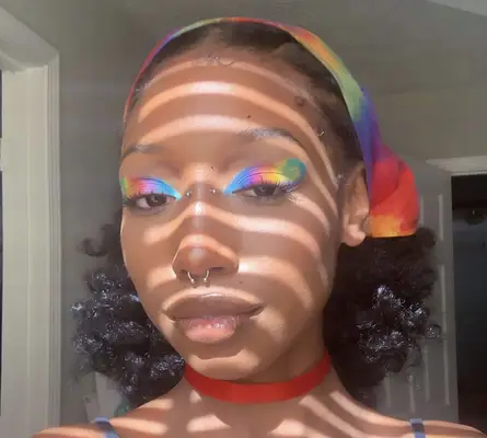 model wears rainbow themed eyeshadow on the lids with blue, pink, orange, yellow, and green