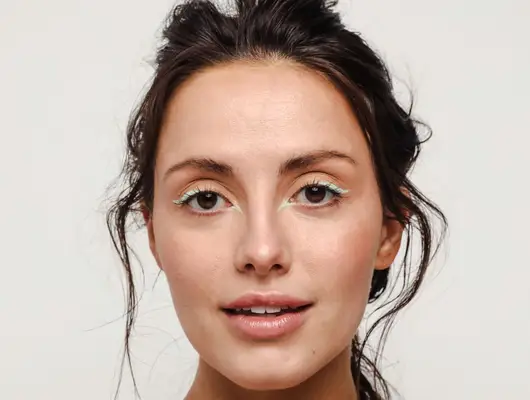 woman wearing pastel green eyeliner looking into camera
