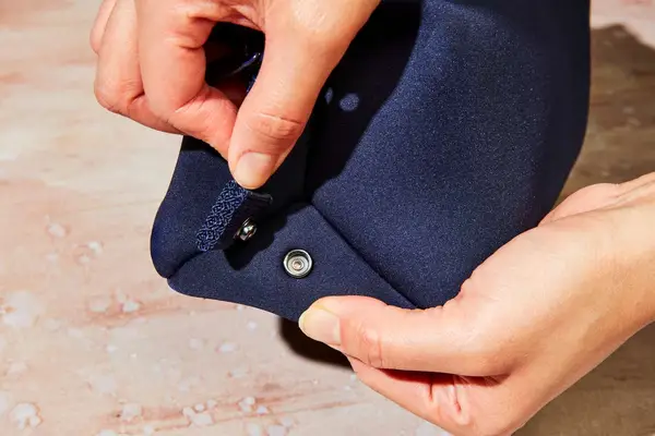 A person unbuttoning a clasp on the Dagne Dover Hunter Toiletry Bag