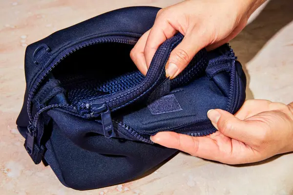 A person velcro-ing a pocket on the Dagne Dover Hunter Toiletry Bag