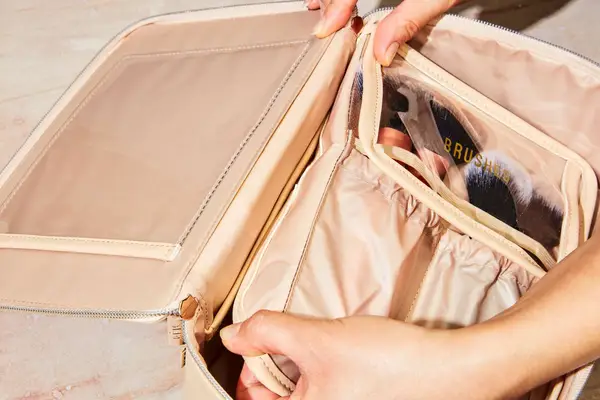 Hands placing a slip pocket containing makeup brushes into the Beis The Cosmetics Case