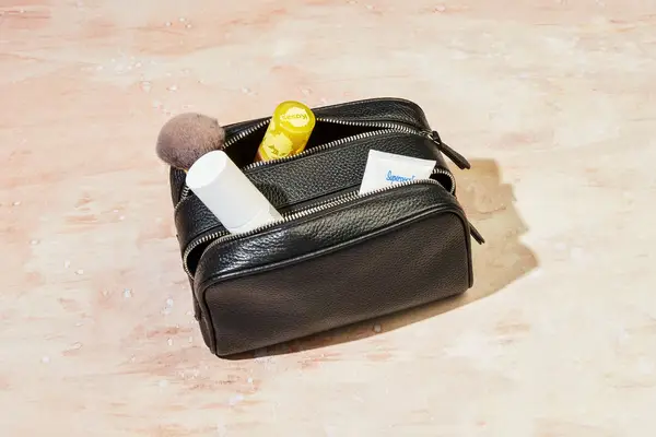 The Royce New York Double Zip Leather Toiletry Bag on a countertop and filled with products