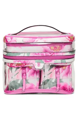 Three makeup bags from Royce, Dagne Dover, and Beis, sitting on a counter with makeup products inside them