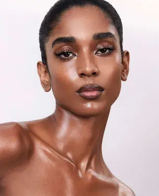 model wears a glossy nude eyeshadow look with long, false eyelashes