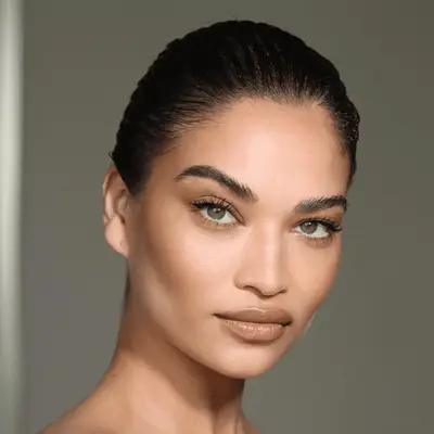 model poses wearing nude eyeshadow look with thin black eyeliner applied to the top lid 