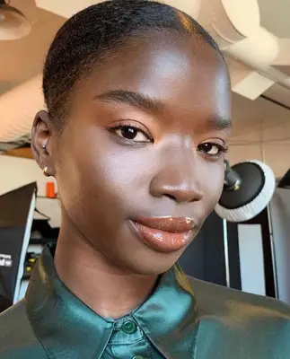 model wears peachy nude eyeshadow look with a peach gloss on the lips