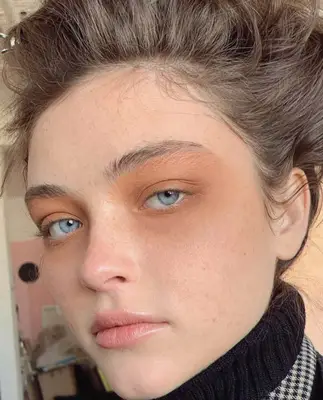 model wears nude eyeshadow all over the top and bottom eyes and natural makeup on the rest of the face