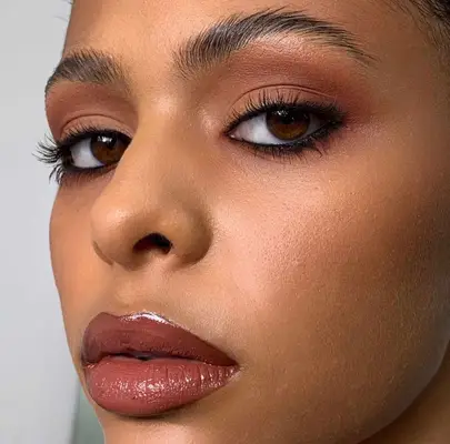 model wears nude eyeshadow look with visible black eyeliner on the top and bottom lashes
