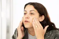 Kosas Cosmetics Tinted Face Oil Comfy Skin Tint displayed on marble countertop with nearby makeup sponge