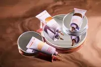 An assortment of Tower 28 SunnyDays SPF 30 Tinted Sunscreen displayed on reflective surface with round mirrors