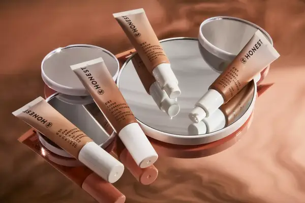 Person applying Honest Beauty CCC Clean Corrective with Vitamin C Tinted Moisturizer SPF 30 to face while looking into mirror