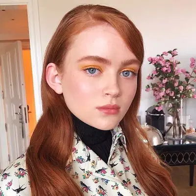 Woman with blue eyes and yellow eyeshadow.