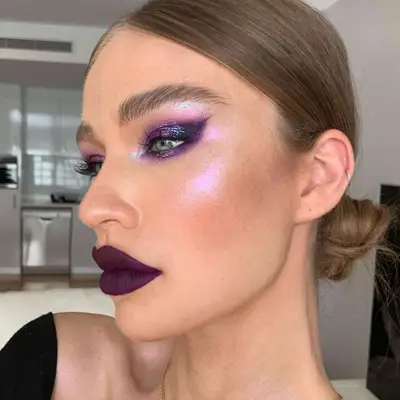 Woman with blue eyes and deep, iridescent purple eyeshadow. 