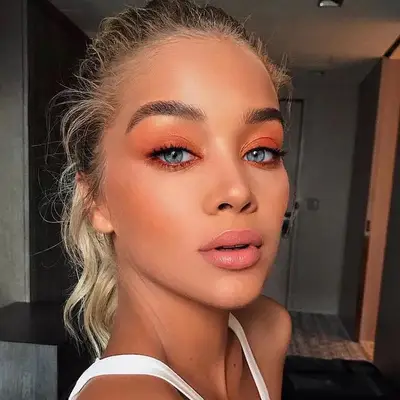Woman with blue eyes and soft orange eyeshadow.