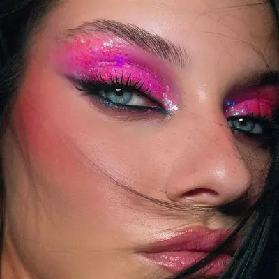 Woman with blue eyes and sparkly pink eyeshadow.