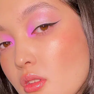 Model with neon eyeshadow, winged eyeliner, and lip gloss