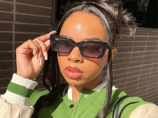 A close-up of a woman wearing sunglassesÂ and an updo with glossy, full, pink lips.Â 