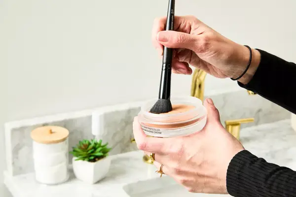 A person applies Chanel Les Beige Healthy Glow Bronzing Cream with a makeup brush