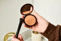 A person uses a makeup brush to apply Guerlain Terracotta Original Bronzing Powder