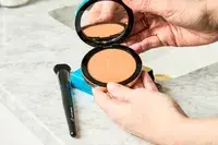 A person holds up the Make Beauty Skin Mimetic Microsuede Powder Bronzer compact