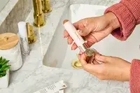 A person removes the cap on the Rare Beauty Warm Wishes Effortless Bronzer Stick