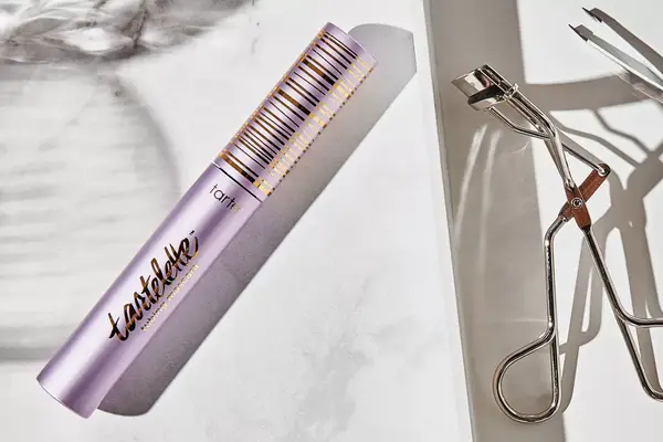Tarte Tartelette Tubing Mascara displayed on marble countertop with nearby eyelash curler