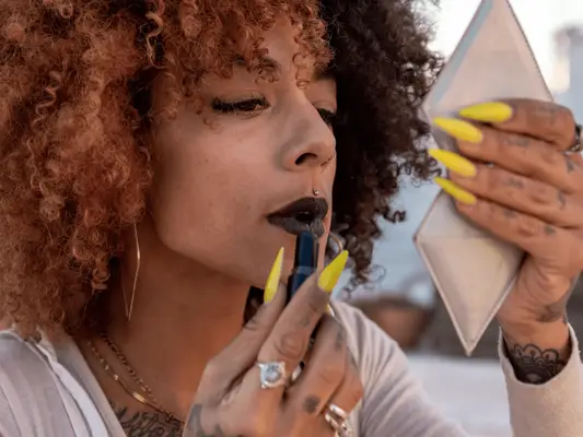 Close up of a woman applying a dark fall lipstick 
