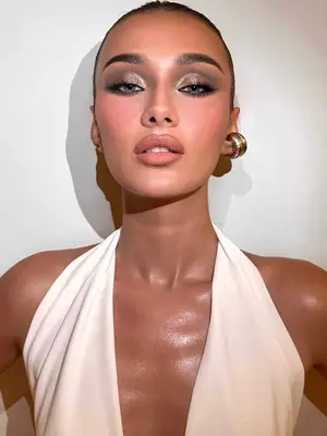 model with slicked back hair, gold hoops and white top