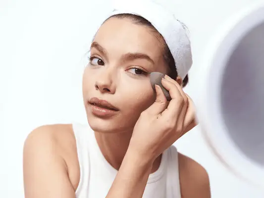 Close up of a woman using a beauty sponge to apply makeup