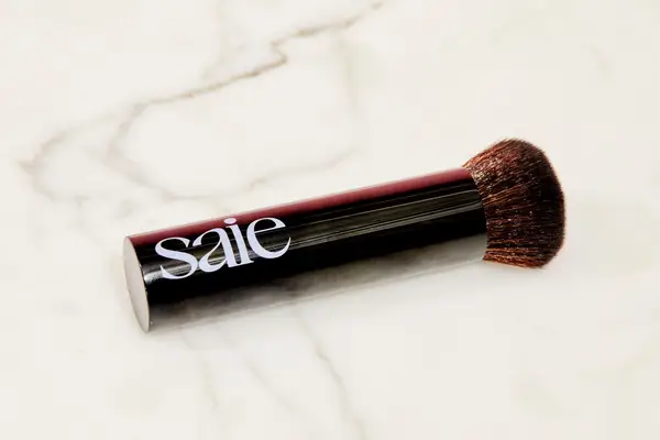 A Saie The Base Brush lying on a marble counter