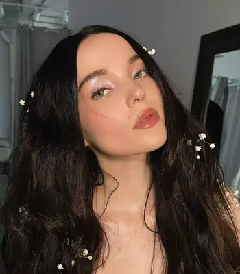 Dove Cameron posing wearing a holographic light shimmering lilac eyeshadow
