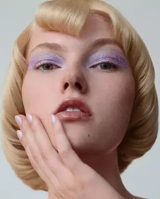 an up close photo of a model wearing lilac eye makeup painted across her eyelids