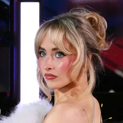 Sabrina Carpenter with a rosy cheek, bold black winged eyeliner, and pink gloss. 