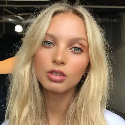 blonde woman with light blush, highlighted eyes, and blurred pink lips