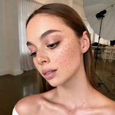 woman with freckles and cool toned eyeshadow and lipstick