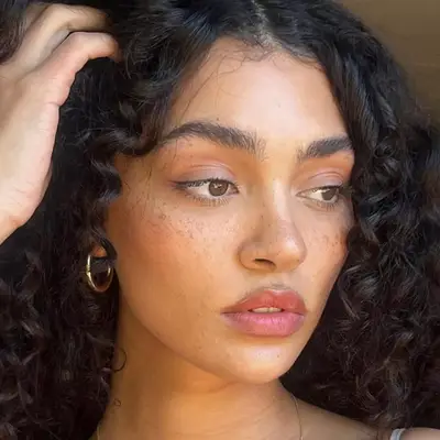 woman with bronzed skin, freckles, berry-toned lips and a subtle winged eyeliner