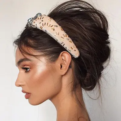 Model wears neutral makeup look with radiant highlighter on temples